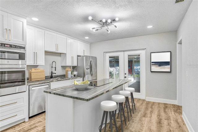 223 Pinehurst Dr, Auburndale, FL 33823 - kitchen with stainless steel appliances, french doors, light wood-type flooring, a breakfast bar area, and a center island