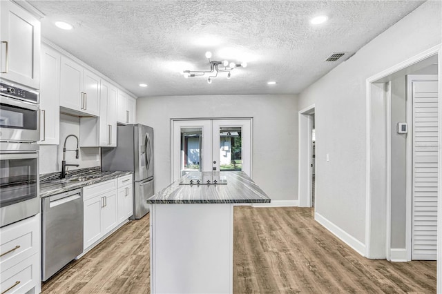 223 Pinehurst Dr, Auburndale, FL 33823 - kitchen featuring stainless steel appliances, french doors, light wood finished floors, a kitchen island, and a textured ceiling