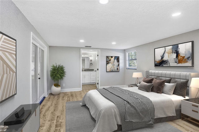 223 Pinehurst Dr, Auburndale, FL 33823 - bedroom with light wood finished floors, recessed lighting, a textured ceiling, and ensuite bath