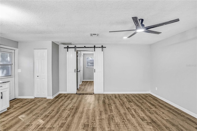 223 Pinehurst Dr, Auburndale, FL 33823 - empty room with a ceiling fan, wood finished floors, a textured ceiling, and a barn door