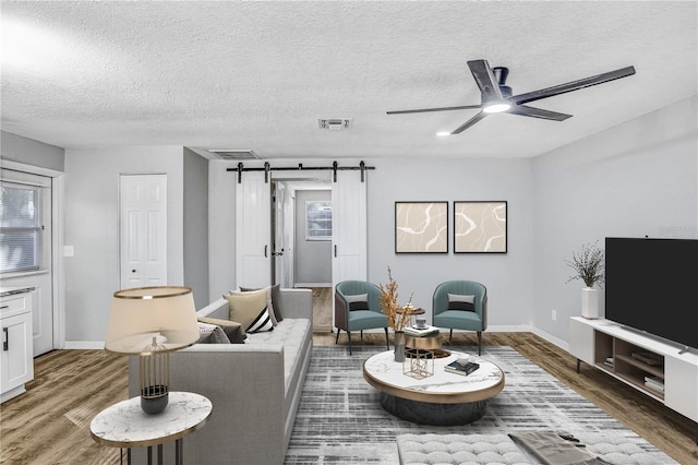223 Pinehurst Dr, Auburndale, FL 33823 - living room featuring a barn door, wood finished floors, plenty of natural light, ceiling fan, and a textured ceiling