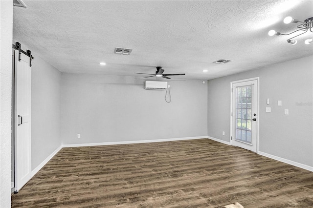223 Pinehurst Dr, Auburndale, FL 33823 - spare room featuring a textured ceiling, dark wood finished floors, a barn door, ceiling fan, and a wall unit AC