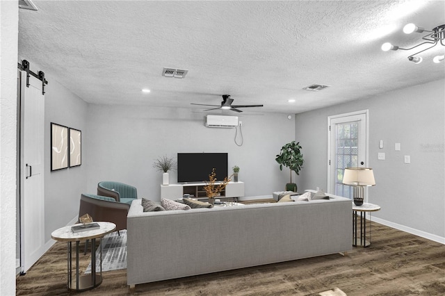 223 Pinehurst Dr, Auburndale, FL 33823 - living area with a textured ceiling, a barn door, wood finished floors, a ceiling fan, and a wall mounted AC