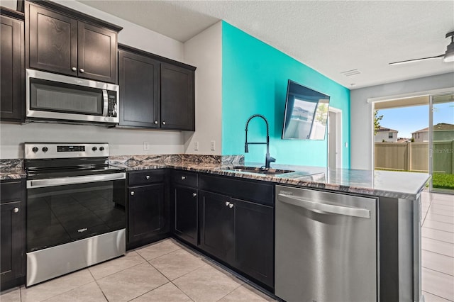 3762 Mossy Limb Ct, Palmetto, FL 34221 - kitchen featuring stainless steel appliances, a peninsula, dark stone counters, light tile patterned flooring, and a textured ceiling