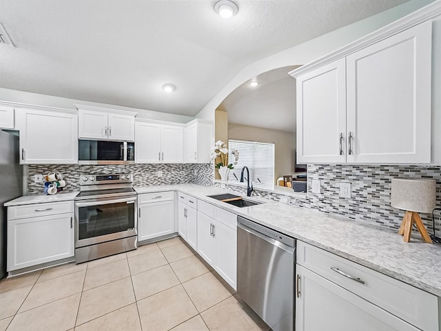 1338 Winding Willow Dr, Trinity, FL 34655 - kitchen with appliances with stainless steel finishes, arched walkways, white cabinetry, light tile patterned flooring, and decorative backsplash