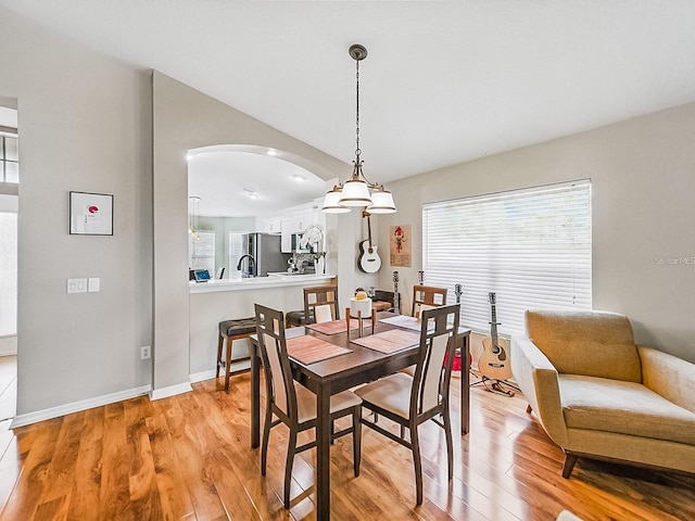 1338 Winding Willow Dr, Trinity, FL 34655 - dining room with arched walkways, light wood finished floors, healthy amount of natural light, and lofted ceiling