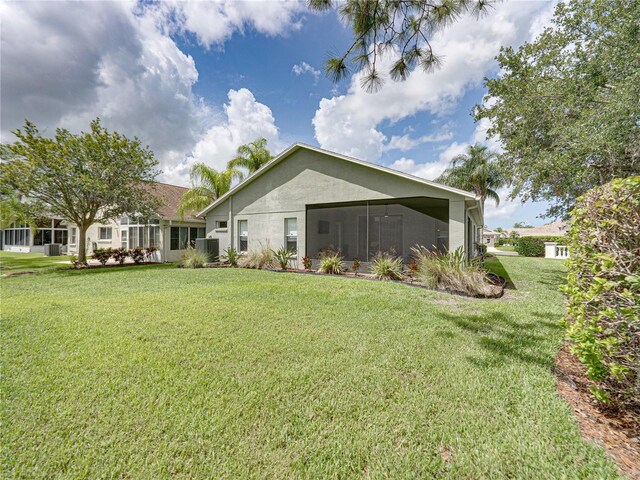 1338 Winding Willow Dr, Trinity, FL 34655 - rear view of house featuring a sunroom, a lawn, and stucco siding