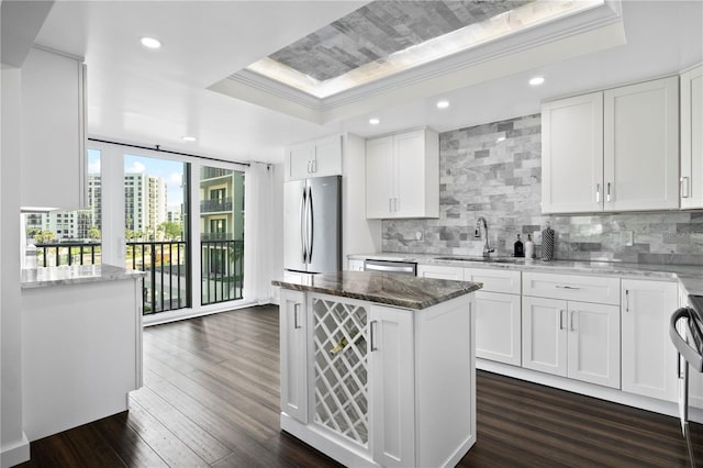 1501 Gulf Blvd Unit 201, Clearwater Beach, FL 33767 - kitchen featuring a tray ceiling, stainless steel appliances, decorative backsplash, dark wood-style floors, and white cabinets