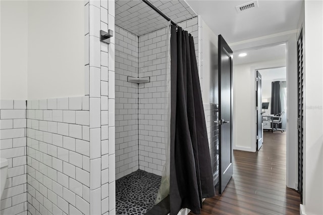 1501 Gulf Blvd Unit 201, Clearwater Beach, FL 33767 - bathroom featuring a tile shower, wood finished floors, tile walls, and wainscoting
