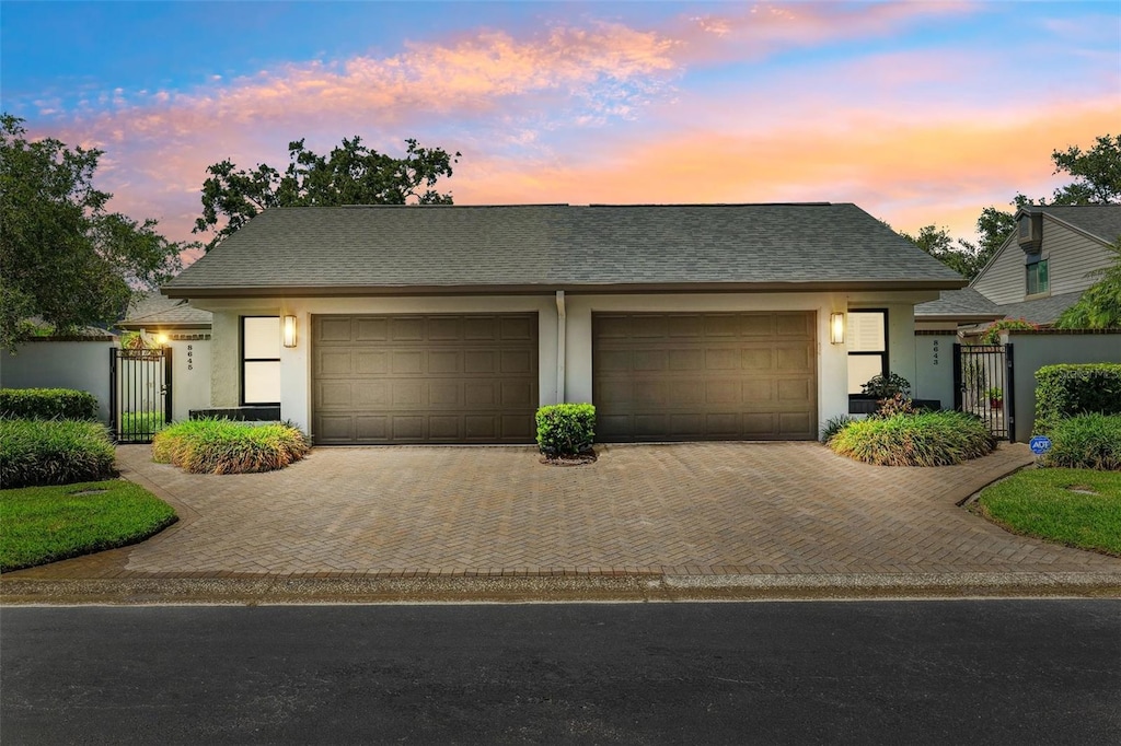 8645 Piper Ln, Seminole, FL 33777 - view of front of property featuring a gate, an attached garage, decorative driveway, stucco siding, and roof with shingles