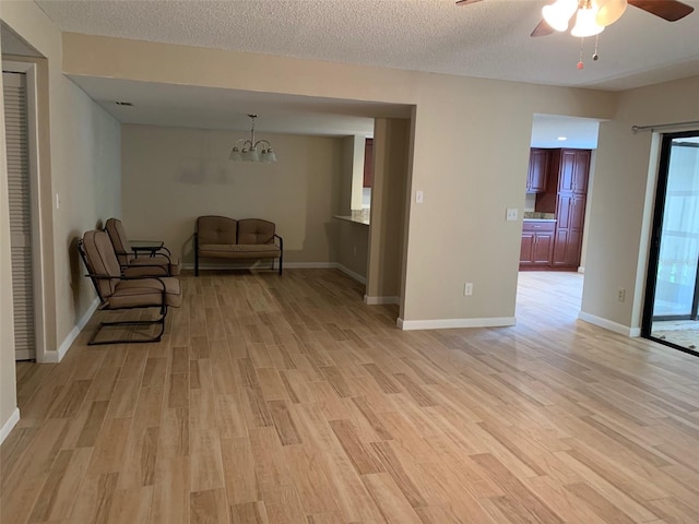 7821 Niagara Ave Unit 2102, Tampa, FL 33617 - living area featuring ceiling fan, light wood finished floors, a chandelier, baseboards, and a textured ceiling