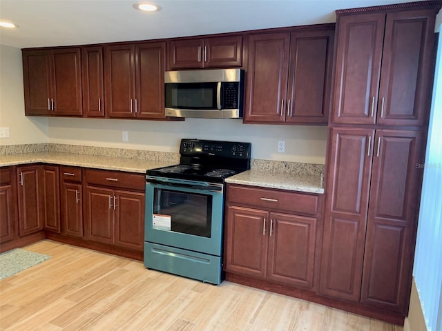 7821 Niagara Ave Unit 2102, Tampa, FL 33617 - kitchen featuring stainless steel microwave, black range with electric stovetop, recessed lighting, light wood-style floors, and light stone counters