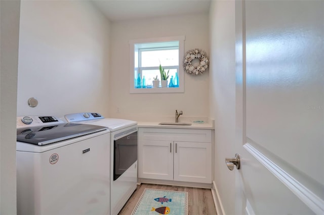 803 Oak Bend Ln, Dunedin, FL 34698 - laundry area featuring washing machine and clothes dryer, light wood finished floors, and cabinet space