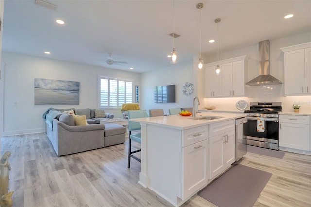 803 Oak Bend Ln, Dunedin, FL 34698 - kitchen featuring appliances with stainless steel finishes, wall chimney range hood, ceiling fan, open floor plan, and light countertops