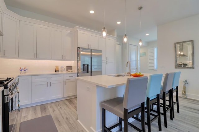 803 Oak Bend Ln, Dunedin, FL 34698 - kitchen featuring stainless steel appliances, light wood-type flooring, white cabinetry, light countertops, and backsplash