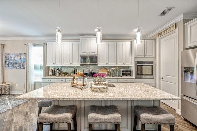3532 Wicket Field Rd, Lutz, FL 33548 - kitchen featuring appliances with stainless steel finishes, light wood finished floors, decorative backsplash, a breakfast bar area, and crown molding