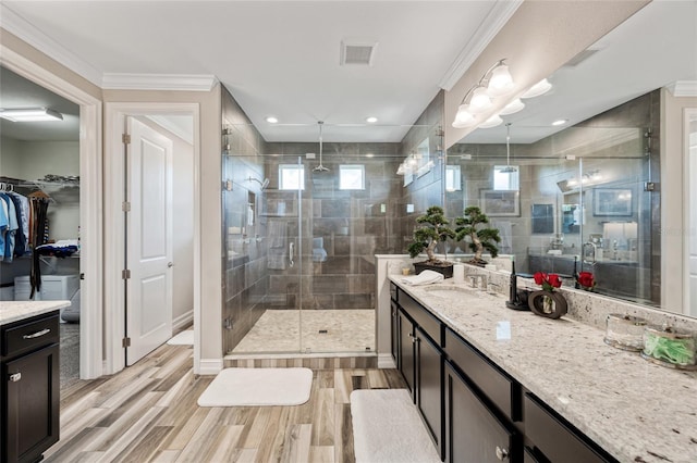 3532 Wicket Field Rd, Lutz, FL 33548 - bathroom featuring a stall shower, vanity, wood finished floors, ornamental molding, and a walk in closet