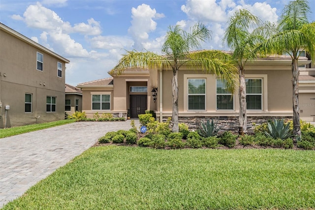 3197 Acacia Bay Ave, Wesley Chapel, FL 33543 - view of front of house with stucco siding, a front lawn, decorative driveway, a tile roof, and stone siding