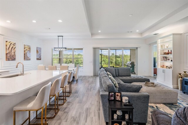 3197 Acacia Bay Ave, Wesley Chapel, FL 33543 - living area with recessed lighting, light wood-type flooring, a chandelier, a raised ceiling, and bar area
