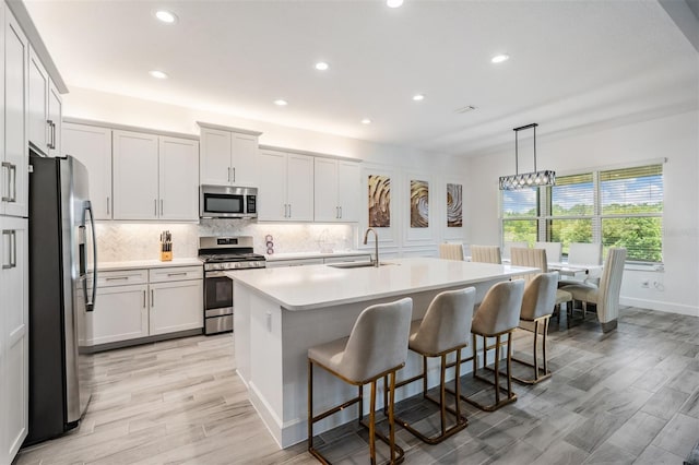 3197 Acacia Bay Ave, Wesley Chapel, FL 33543 - kitchen featuring appliances with stainless steel finishes, tasteful backsplash, light countertops, recessed lighting, and an island with sink