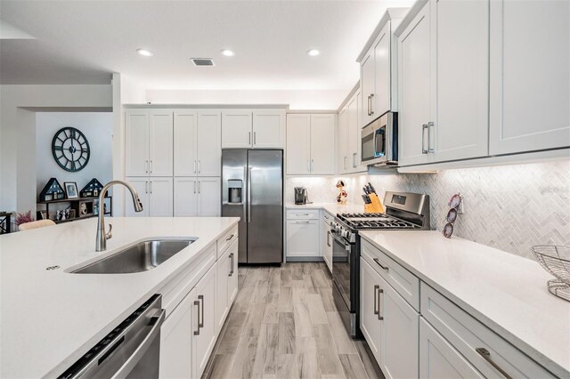 3197 Acacia Bay Ave, Wesley Chapel, FL 33543 - kitchen featuring stainless steel appliances, light countertops, light wood-type flooring, decorative backsplash, and white cabinets