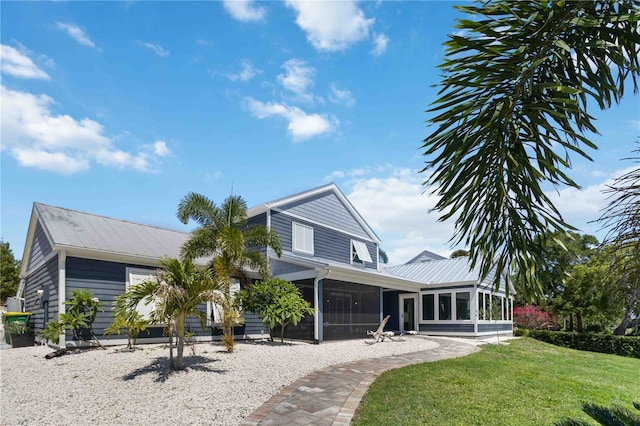 711 N Indian River Dr, Cocoa, FL 32922 - rear view of property featuring a sunroom, a yard, and metal roof