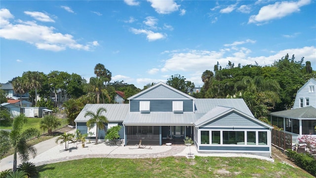 711 N Indian River Dr, Cocoa, FL 32922 - rear view of house featuring a sunroom, a yard, and metal roof