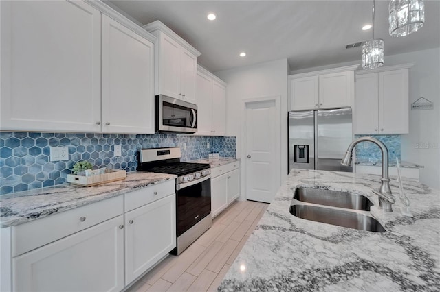 5415 Limelight Dr, Apollo Beach, FL 33572 - kitchen featuring appliances with stainless steel finishes, white cabinets, hanging light fixtures, light stone countertops, and recessed lighting