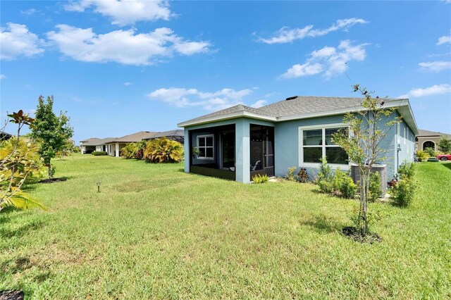 5415 Limelight Dr, Apollo Beach, FL 33572 - back of property with a sunroom, a yard, and stucco siding