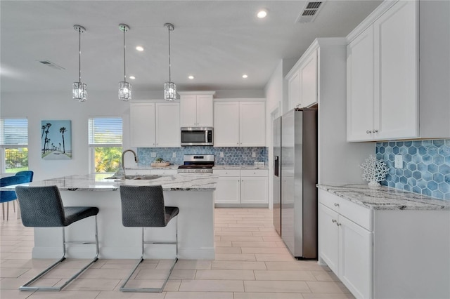 5415 Limelight Dr, Apollo Beach, FL 33572 - kitchen with stainless steel appliances, tasteful backsplash, white cabinetry, a kitchen breakfast bar, and recessed lighting