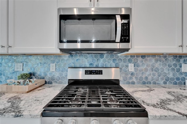 5415 Limelight Dr, Apollo Beach, FL 33572 - kitchen view of appliances with stainless steel finishes, white cabinets, backsplash, and light stone countertops