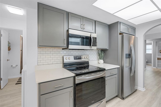 2481 12th Ave SW, Largo, FL 33770 - kitchen with stainless steel appliances, gray cabinetry, arched walkways, light countertops, and tasteful backsplash