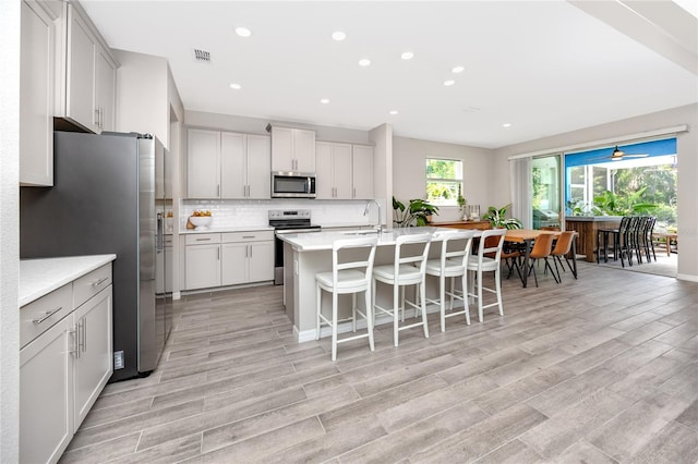 8423 Praise Dr, Tampa, FL 33625 - kitchen with appliances with stainless steel finishes, light countertops, a breakfast bar, tasteful backsplash, and recessed lighting