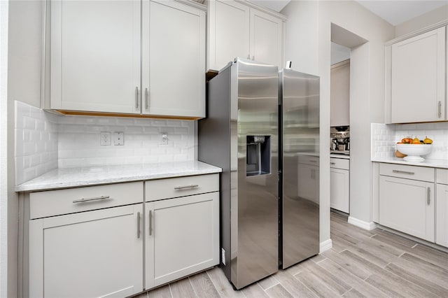 8423 Praise Dr, Tampa, FL 33625 - kitchen featuring stainless steel fridge, tasteful backsplash, light wood-style flooring, light stone countertops, and white cabinetry