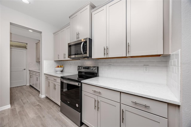 8423 Praise Dr, Tampa, FL 33625 - kitchen with stainless steel appliances, light wood-style flooring, decorative backsplash, light stone counters, and recessed lighting