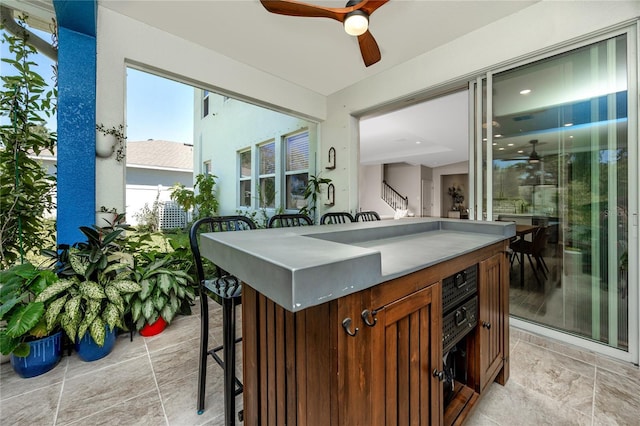 8423 Praise Dr, Tampa, FL 33625 - kitchen featuring ceiling fan, a kitchen breakfast bar, light stone finish floors, and a kitchen island