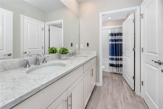 8423 Praise Dr, Tampa, FL 33625 - full bathroom with double vanity, toilet, wood finished floors, shower / tub combo, and baseboards
