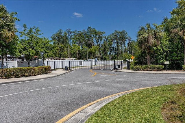 8423 Praise Dr, Tampa, FL 33625 - view of asphalt road with sidewalks, curbs, a gate, view of scattered trees, and traffic signs