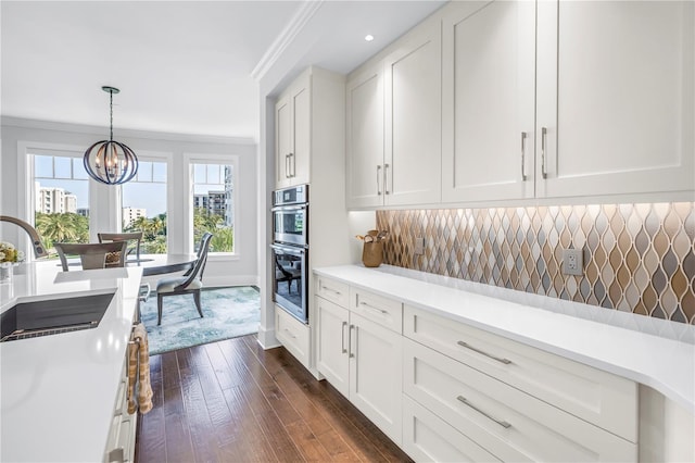 125 Belleview Blvd Unit 203, Belleair, FL 33756 - kitchen with crown molding, dark wood-type flooring, a chandelier, light countertops, and white cabinets