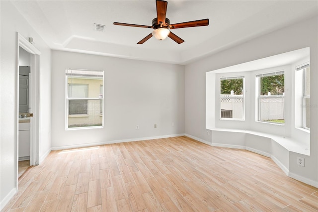 17342 Lawn Orchid Loop, Land O Lakes, FL 34638 - empty room with light wood-style flooring, a tray ceiling, a ceiling fan, and baseboards