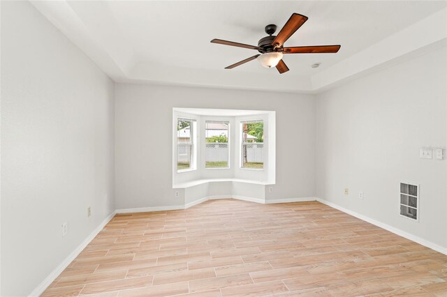 17342 Lawn Orchid Loop, Land O Lakes, FL 34638 - spare room with a ceiling fan, light wood-type flooring, a tray ceiling, and baseboards