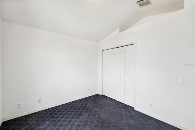 899 Addison Dr NE, Saint Petersburg, FL 33716 - unfurnished bedroom with lofted ceiling, dark carpet, and a closet