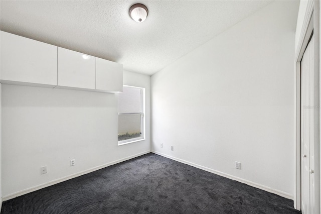 899 Addison Dr NE, Saint Petersburg, FL 33716 - unfurnished bedroom featuring dark colored carpet and a textured ceiling