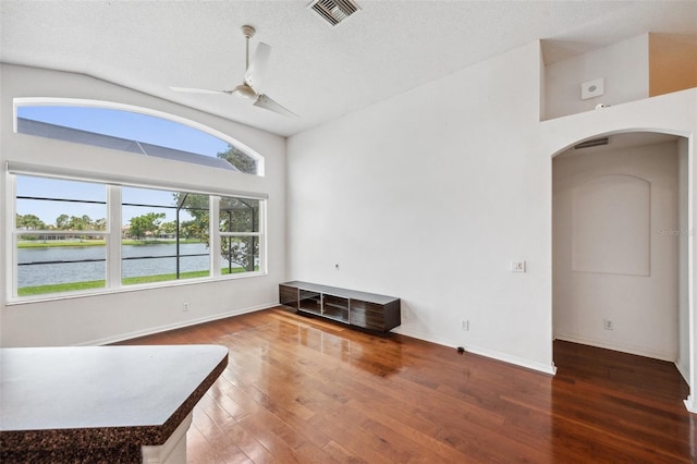 899 Addison Dr NE, Saint Petersburg, FL 33716 - unfurnished living room with arched walkways, wood finished floors, ceiling fan, vaulted ceiling, and a water view