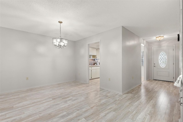 440 Lakeview Dr Unit 34, Palm Harbor, FL 34683 - empty room featuring light wood-type flooring, a chandelier, and a textured ceiling