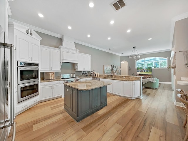 15024 Eaglepark Pl, Lithia, FL 33547 - kitchen featuring a peninsula, white cabinetry, stainless steel appliances, light wood-style floors, and ornamental molding