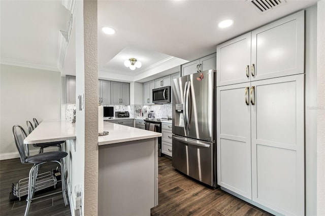 400 Island Way Unit 502, Clearwater Beach, FL 33767 - kitchen featuring stainless steel appliances, ornamental molding, a peninsula, dark wood-style flooring, and a tray ceiling