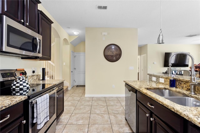 10216 Summer Azure Dr, Riverview, FL 33578 - kitchen featuring stainless steel appliances, arched walkways, light stone countertops, and dark brown cabinetry