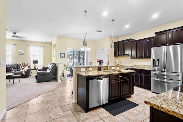 10216 Summer Azure Dr, Riverview, FL 33578 - kitchen with appliances with stainless steel finishes, open floor plan, an island with sink, light stone countertops, and decorative light fixtures