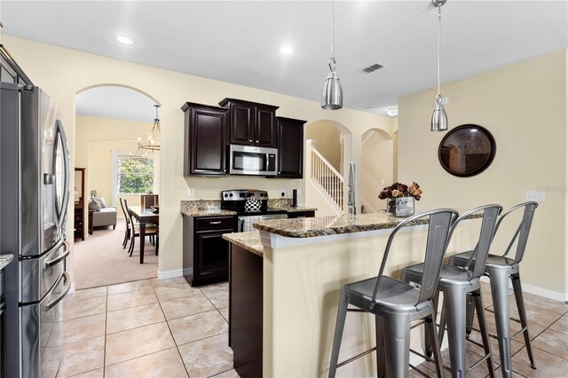 10216 Summer Azure Dr, Riverview, FL 33578 - kitchen with stainless steel appliances, a kitchen breakfast bar, arched walkways, stone countertops, and pendant lighting